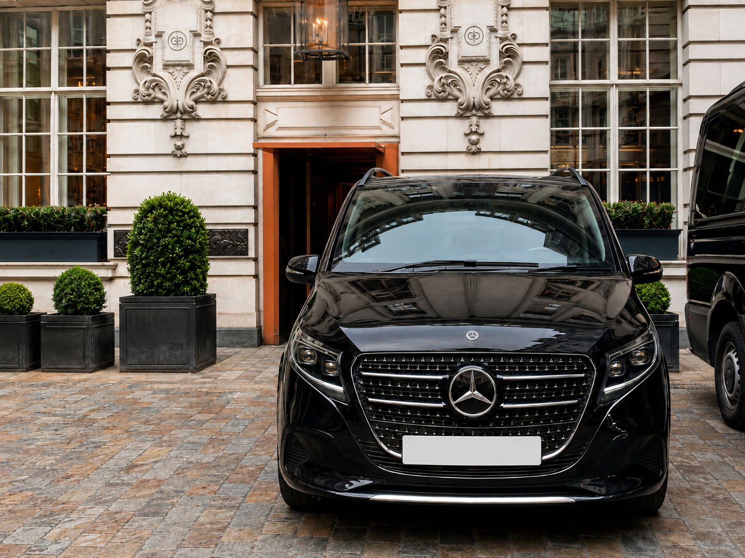 Black Mercedes V-Class chauffeur vehicle outside a luxury hotel entrance