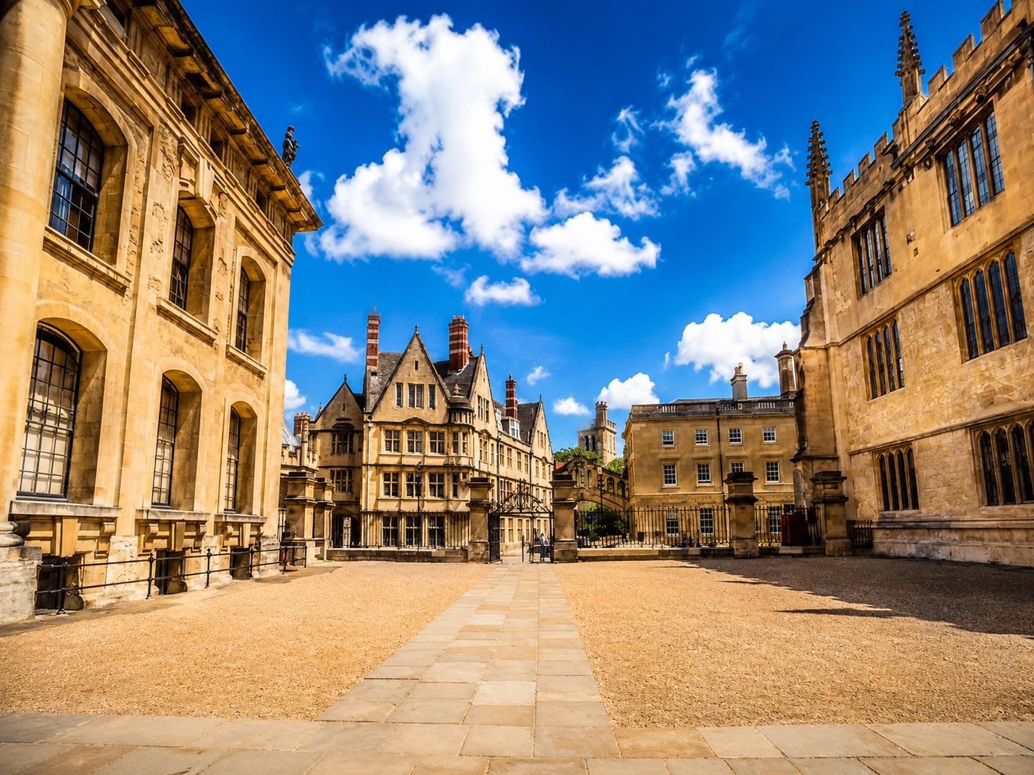 Historic Oxford university buildings surrounding a traditional stone courtyard under a blue sky.